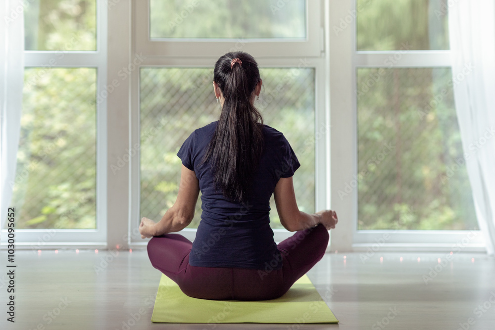 Woman practicing yoga and meditation in lotus pose on yoga mat, relaxed. Woman practicing yoga and meditation in lotus pose on yoga mat, relaxed.
