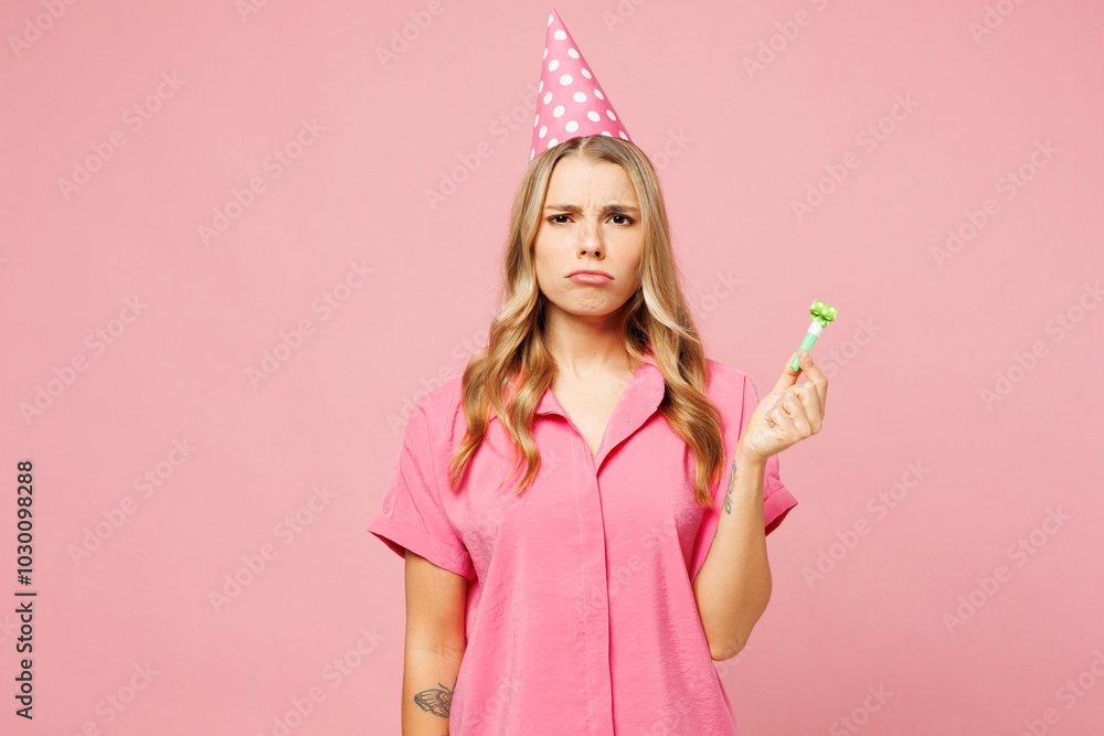 Young sad dissatisfied upset displeased woman wear shirt cone hat celebrating birthday holiday hold in hand blowing pipe look camera isolated on plain pastel light pink background. Lifestyle concept. Young sad dissatisfied upset displeased woman wear shirt cone hat celebrating birthday holiday hold in hand blowing pipe look camera isolated on plain pastel light pink background. Lifestyle concept.