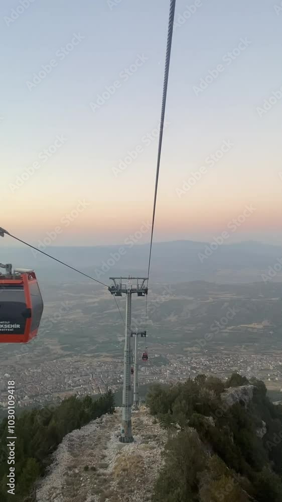 A dramatic view of a cable car journey at sunset over the forested slopes of Bursa, offering a unique aerial perspective that connects the urban area with the natural landscape of Uludağ.