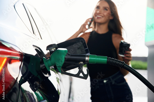 Foto Talking by a phone. A young woman at a gas station with her car