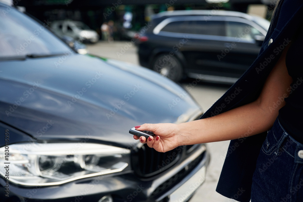 Focused close up view of woman hand that is holding key in front of the car Focused close up view of woman hand that is holding key in front of the car