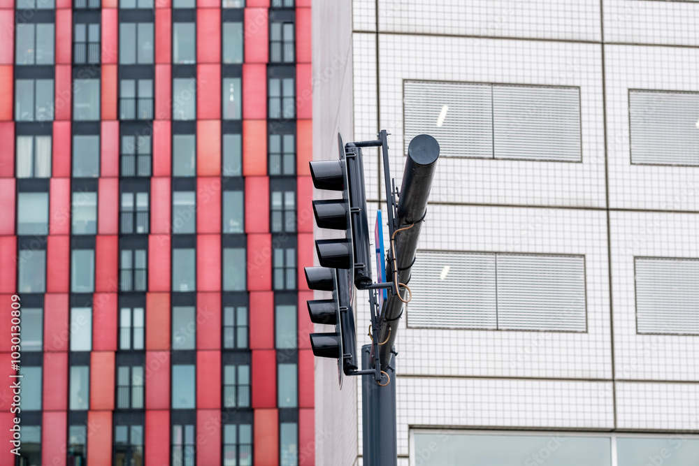 A vibrant red and black building facade stands next to a series of traffic lights in an urban setting, showcasing the lively contrast in colors and design elements. A vibrant red and black building facade stands next to a series of traffic lights in an urban setting, showcasing the lively contrast in colors and design elements.