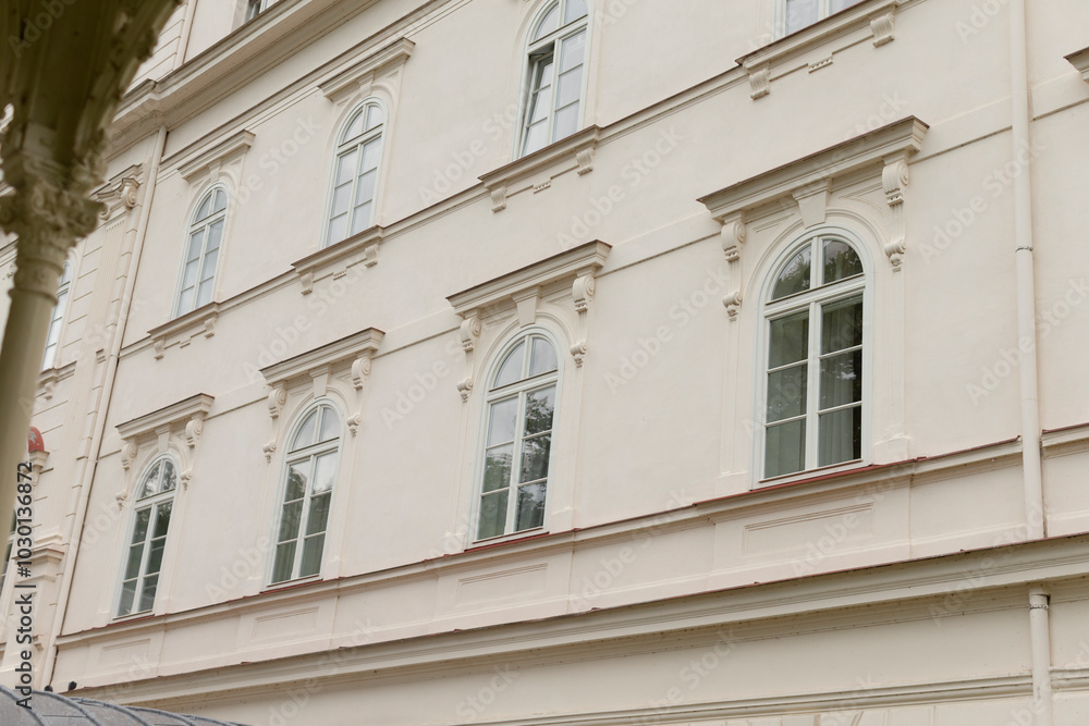 There is a large, striking white building that features numerous windows and has a beautiful tree situated in front of it There is a large, striking white building that features numerous windows and has a beautiful tree situated in front of it