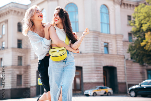 Two young beautiful smiling female in trendy summer clothes. Sexy carefree women posing in the street. Positive models having fun, hugging in sunny day. With bright makeup and red lips