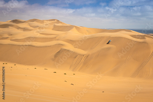 Sandwich Harbour in Namibia mit einem 4x4 Fahrzeug - ein Geländefahrzeug fährt über riesige Dünen, Wüstenfahrt in Afrika