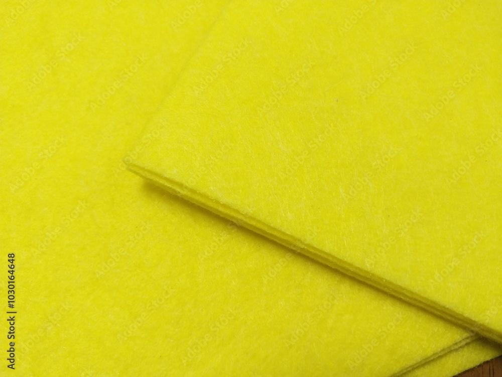 a close-up of two sheets of bright yellow paper or card stock. They are slightly overlapping each other, with one sheet placed on top of the other at an angle. The texture appears smooth and the color a close-up of two sheets of bright yellow paper or card stock. They are slightly overlapping each other, with one sheet placed on top of the other at an angle. The texture appears smooth and the color