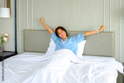 Woman stretching in bed after waking up