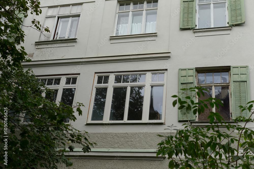 A charming white building featuring elegant green shutters adorning the windows, creating a delightful contrast in its facade and surroundings A charming white building featuring elegant green shutters adorning the windows, creating a delightful contrast in its facade and surroundings
