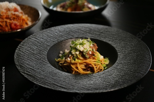 Gourmet pasta dish on black plate photo