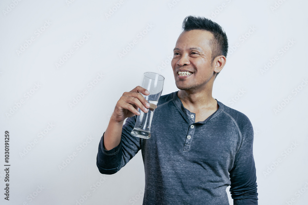 Young Asian man drinking water while standing on white background. Young Asian man drinking water while standing on white background.