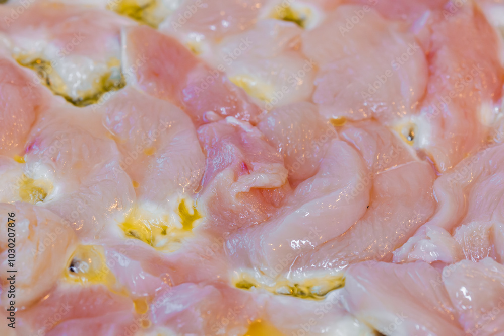 closeup full-frame background of raw chicken breast meat just starting to roast.