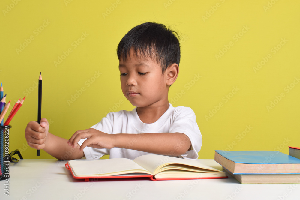 Portrait of an Asian boy studying isolated on a yellow background Portrait of an Asian boy studying isolated on a yellow background