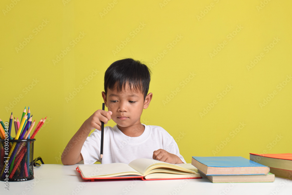 Portrait of an Asian boy studying isolated on a yellow background Portrait of an Asian boy studying isolated on a yellow background