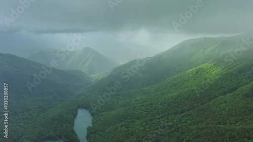 Aerial view of dark clouds and sun rays over summer green mountains landscape, Montenegro, 4k