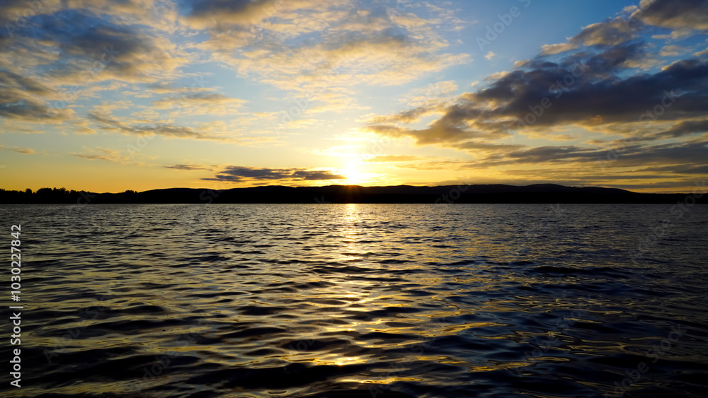 Obraz premium Sunset on the lake with a mirror image of the sun and sky on the water. Landscape view of the lake, calm environment. Beauty is in nature.