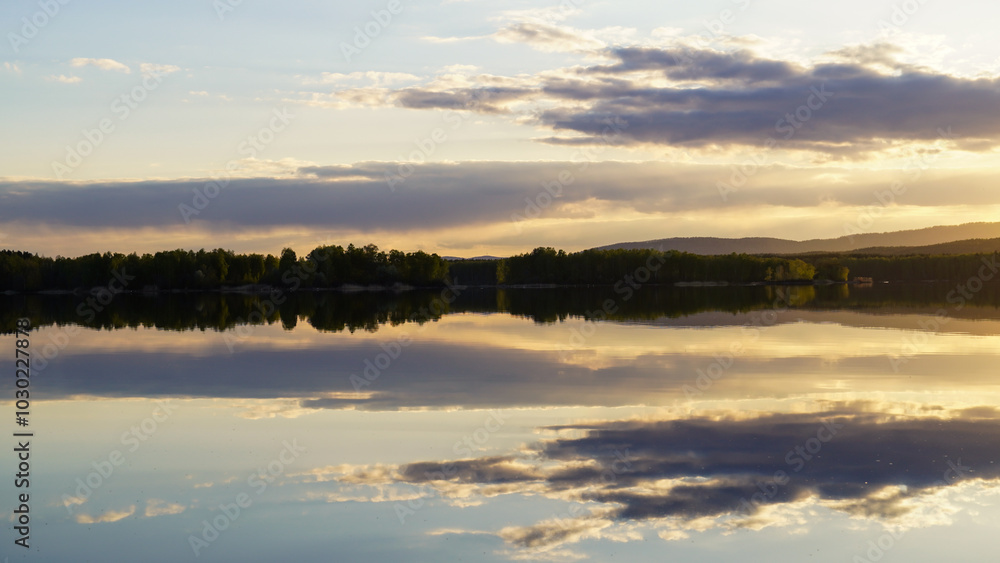 Sunset on the lake with a mirror image of the cloudy sky on the surface of the water. The concept of love for nature. Sunset on the lake with a mirror image of the cloudy sky on the surface of the water. The concept of love for nature.
