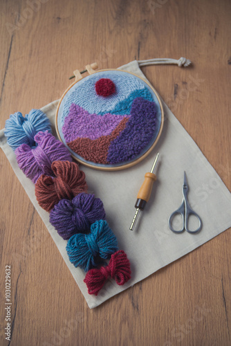 Layout of small woolen skeins placed in a row, punch needle, scissors and clorful embroidery in a hoop.