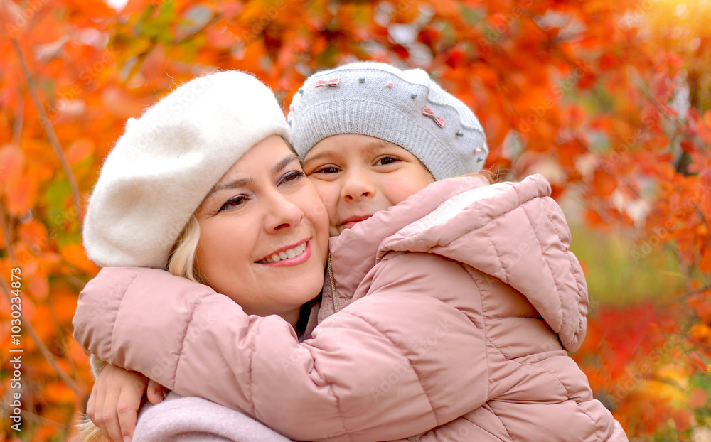 Happy mother and little daughter in an autumn park together, wearing birets and coats. Bright autumn background, orange and yellow foliage. Family and relationships concept Happy mother and little daughter in an autumn park together, wearing birets and coats. Bright autumn background, orange and yellow foliage. Family and relationships concept