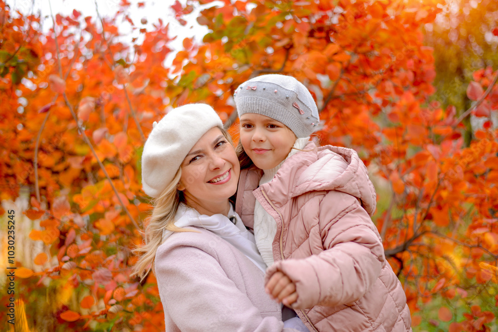 Happy mother and little daughter in an autumn park together, wearing birets and coats. Bright autumn background, orange and yellow foliage. Family and relationships concept Happy mother and little daughter in an autumn park together, wearing birets and coats. Bright autumn background, orange and yellow foliage. Family and relationships concept