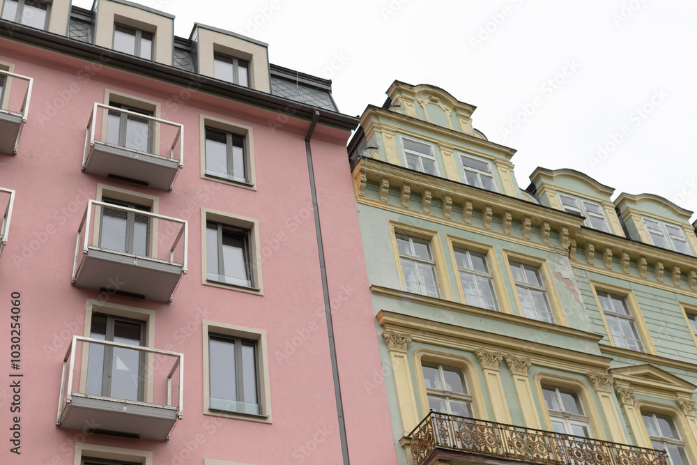 There is a pink building with multiple balconies situated right next to a green building that also has balconies adorning its facade There is a pink building with multiple balconies situated right next to a green building that also has balconies adorning its facade