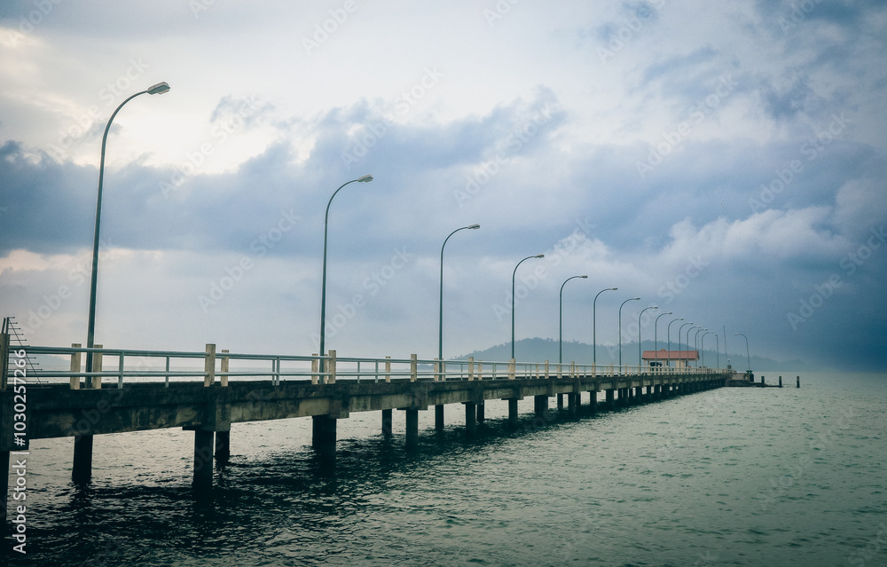 A tranquil evening at Kota Kinabalu pier surrounded by cloudy skies and calm waters A tranquil evening at Kota Kinabalu pier surrounded by cloudy skies and calm waters