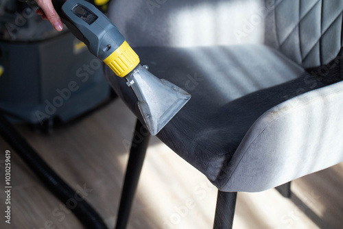 Dry cleaning gray soft chairs made of fabric upholstery with a washing vacuum cleaner. Cleaning company services, close-up photo