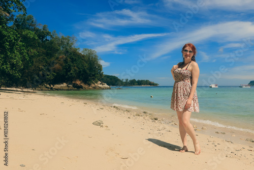 A tourist enjoys a sunny day at the beautiful beach in Malaysia, savoring the tropical atmosphere and clear blue waters