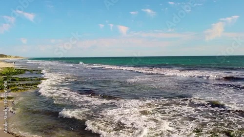 Crystal clear waves lap against the rocky shoreline of Clatons Beach in Mindarie, Australia photo