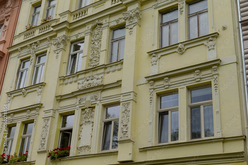 There is a bright yellow building featuring numerous windows along with vibrant flowers adorning the balconies, creating a charming atmosphere There is a bright yellow building featuring numerous windows along with vibrant flowers adorning the balconies, creating a charming atmosphere