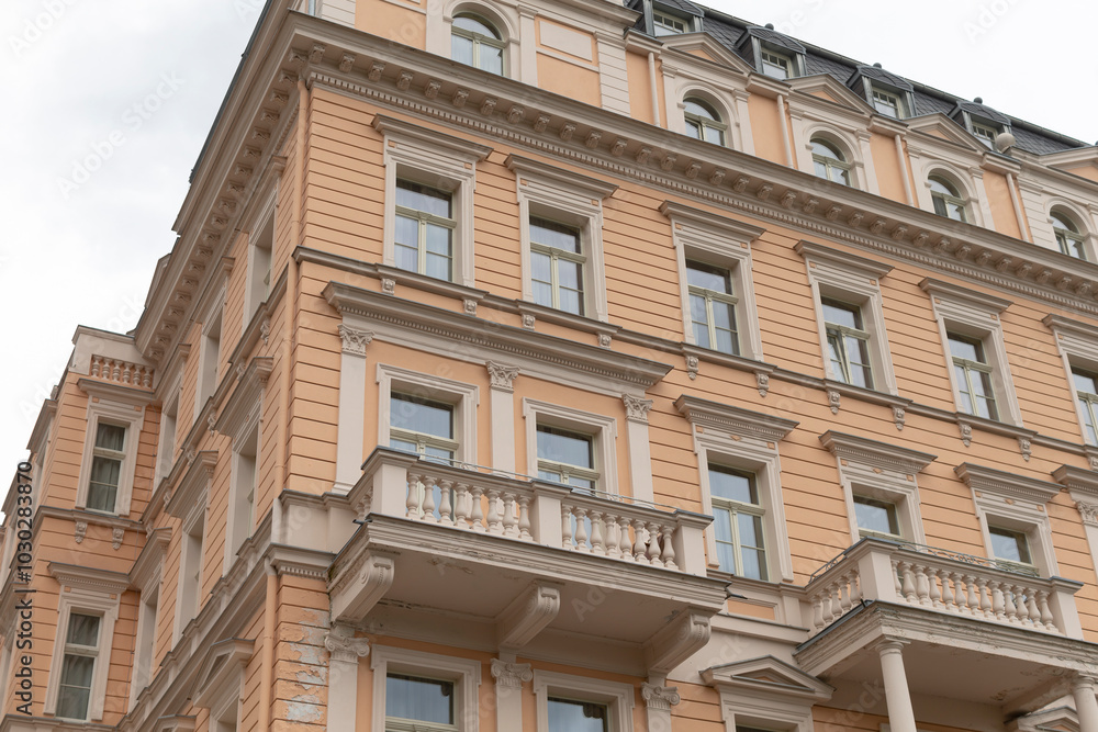 A large and impressive building that features numerous windows and multiple balconies, showcasing its architectural design in the city skyline A large and impressive building that features numerous windows and multiple balconies, showcasing its architectural design in the city skyline