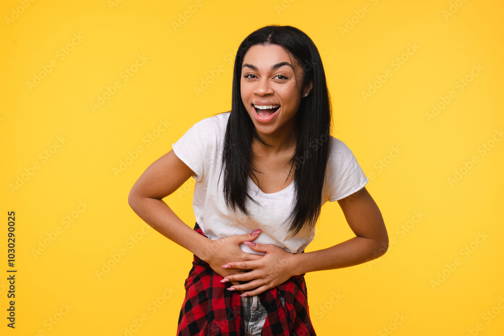 Obraz premium Emotional happy young african american woman black girl female afro student laughing out loud alone express positive emotion wearing casual clothes isolated over yellow background.