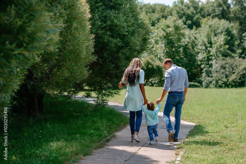Happy African-American and European family walking and playing together in the park. Black family walking down the road holding hands