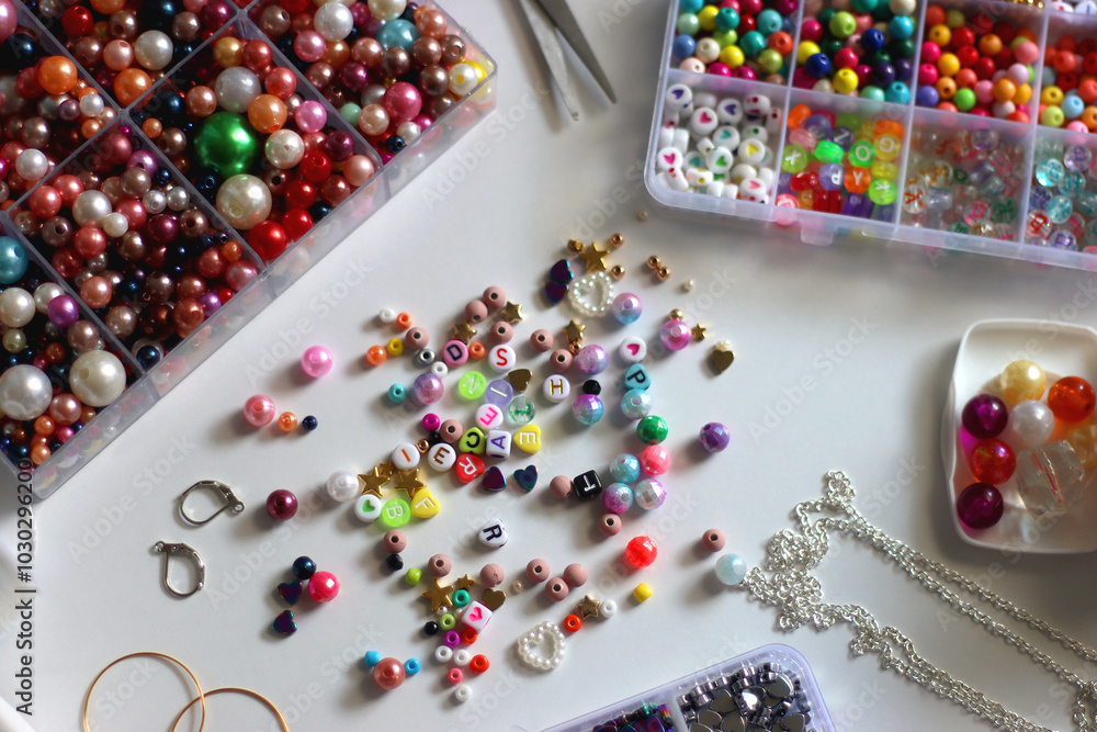 Colorful beads, letter beads, threads and other jewelry making supplies on white background. Making friendship bracelets concept. Selective focus.
