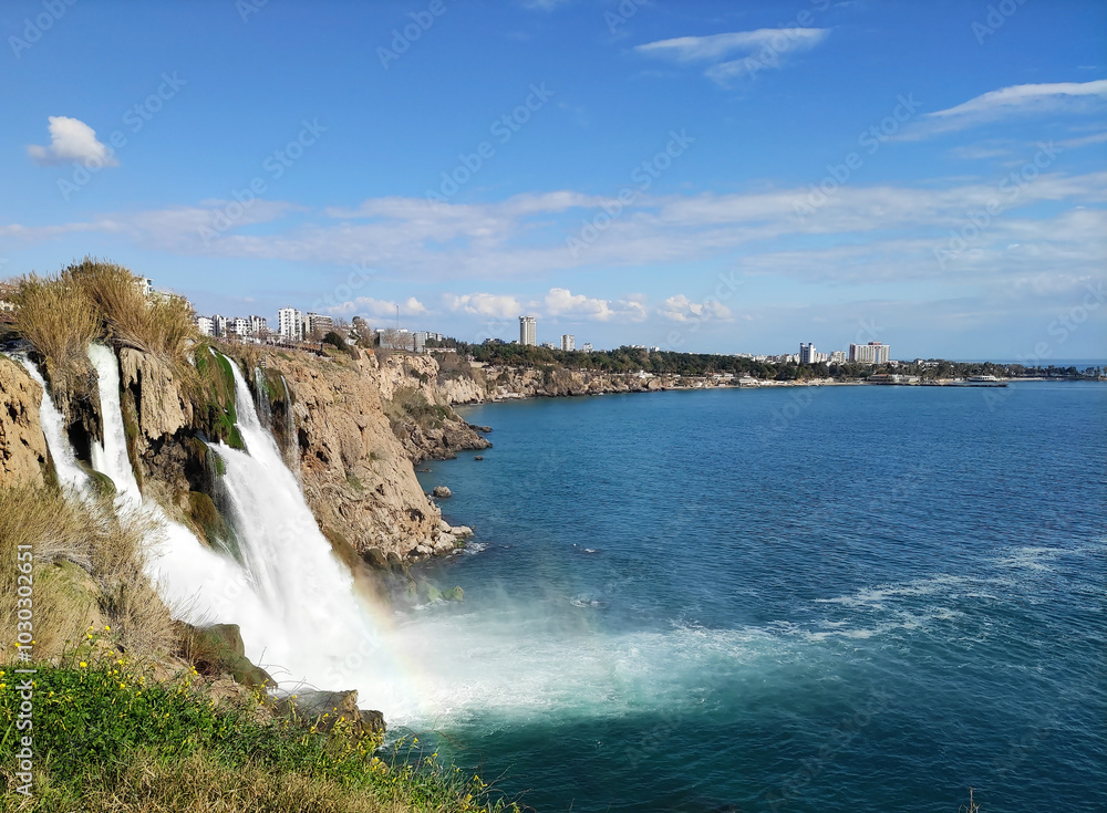 Obraz premium A fast waterfall falling from a mountain cliff into the blue sea