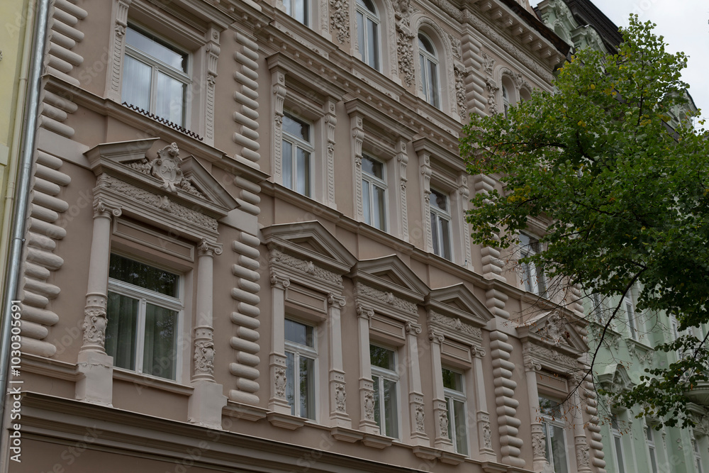 Fototapeta premium A large building featuring numerous windows and having a tree prominently situated in front of it that adds to its appeal
