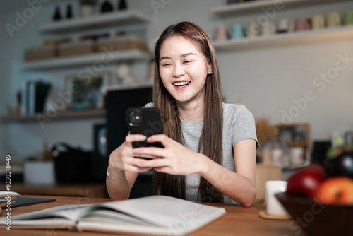 Happy asian woman relax using smartphone sits at home. Young asian girl working or study, chatting social network, work from home.