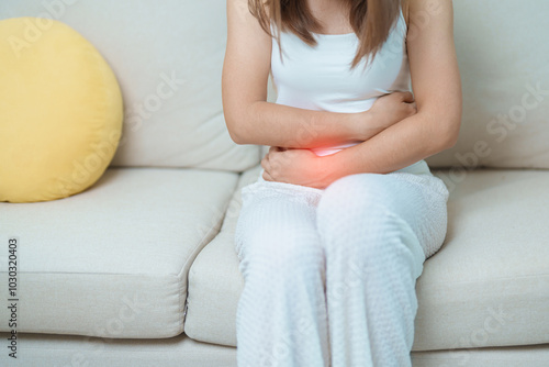 woman having abdomen ache due to Stomach pain, digestion with constipation or Diarrhea from food poisoning, female problem and Endometriosis, Hysterectomy, Stomachache and Menstrual on sofa at home