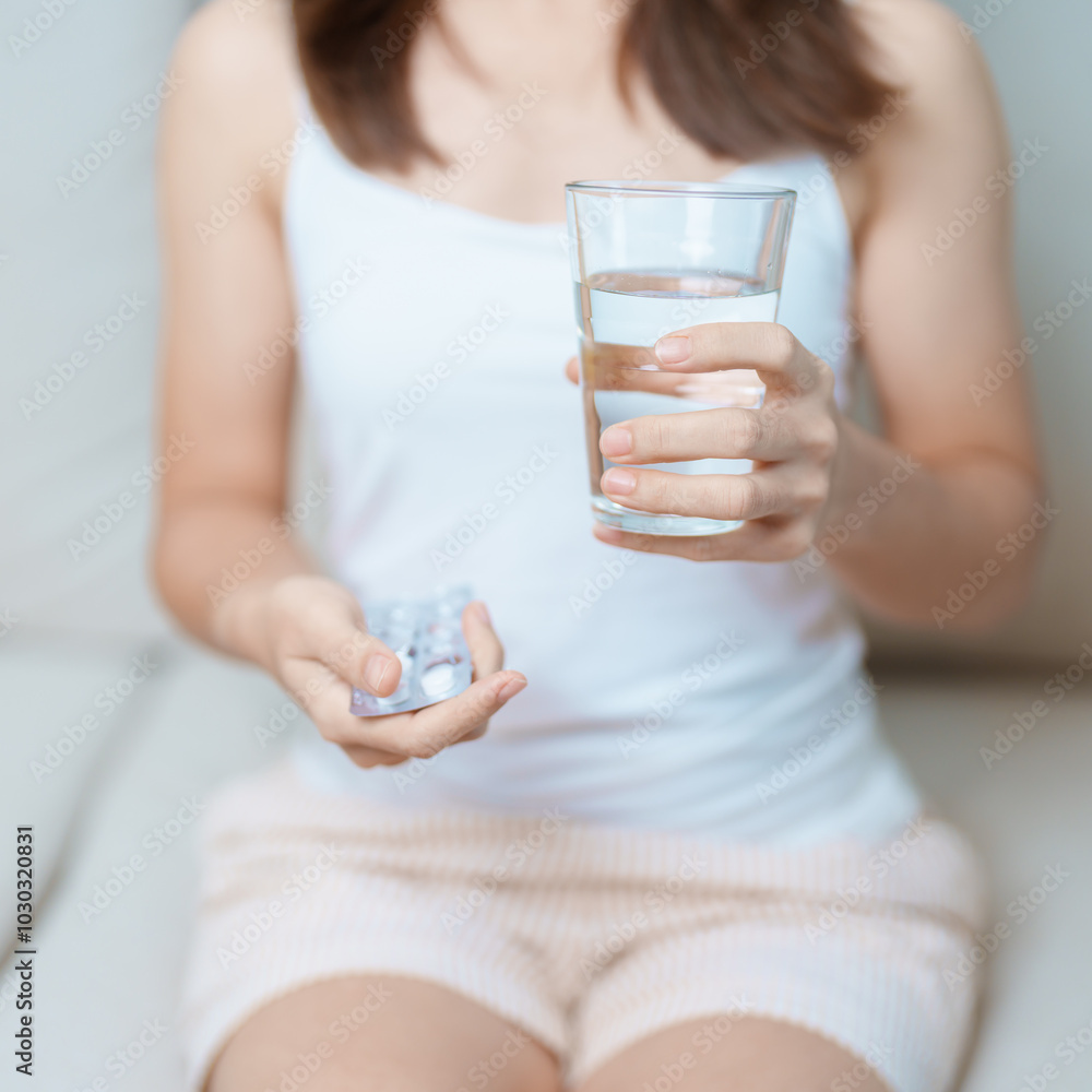 woman hand holding medicine painkiller pill and water glass on the sofa at home, taking for headaches, stomach ache, Diarrhea Pain from food poisoning, Endometriosis, Hysterectomy and Menstrual woman hand holding medicine painkiller pill and water glass on the sofa at home, taking for headaches, stomach ache, Diarrhea Pain from food poisoning, Endometriosis, Hysterectomy and Menstrual