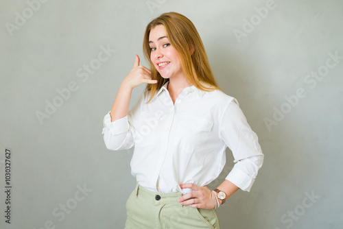 Attractive Caucasian woman smiling and gesturing for someone to call her