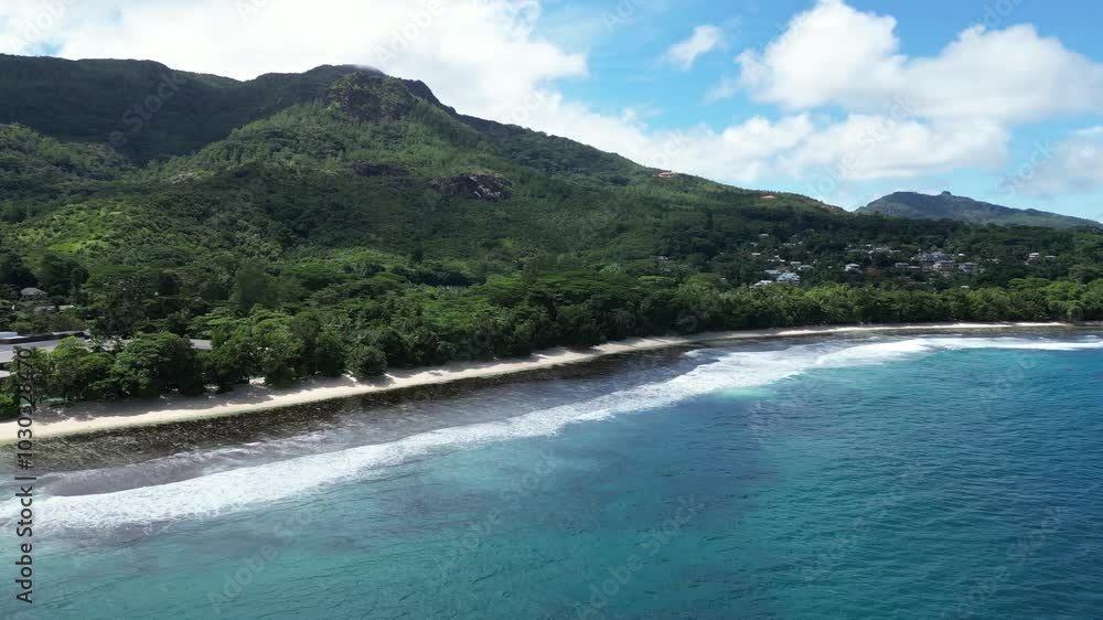 Aerial view showcasing the vibrant green trees and pristine beach coastline of Mahe Island, Seychelles. Push forward shot Aerial view showcasing the vibrant green trees and pristine beach coastline of Mahe Island, Seychelles. Push forward shot