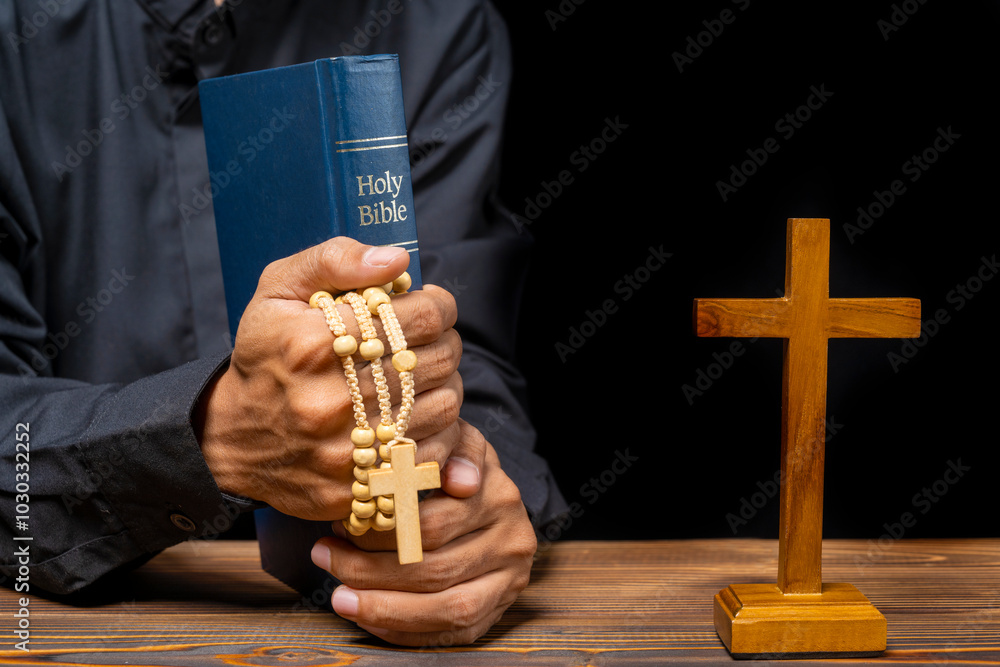 Obraz premium Man praying with rosary beads, religion cross and holy bible on wooden table. Symbol of faith and worship in God. People christianity prayer in church