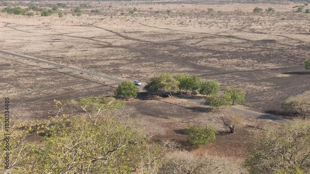 The car drove in the middle of a dry grassland, a barren land in the dry season The car drove in the middle of a dry grassland, a barren land in the dry season