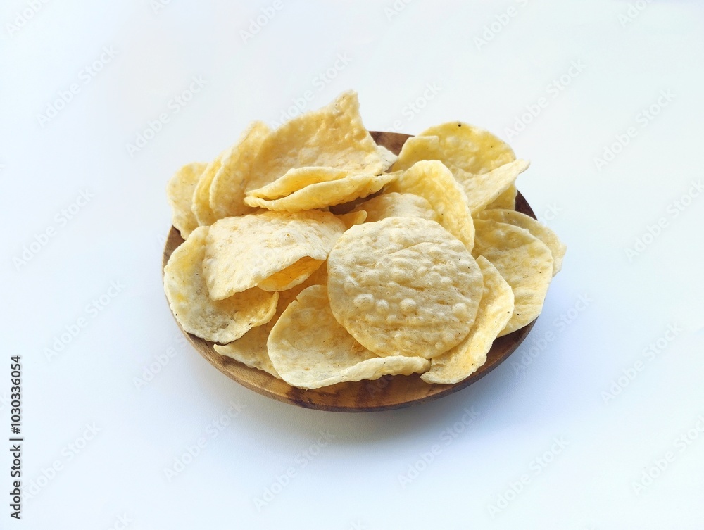 Opak singkong or cassava chips in wooden plate isolated on white background. Indonesian traditional foods Opak singkong or cassava chips in wooden plate isolated on white background. Indonesian traditional foods