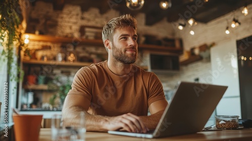 Man seated at a rustic café table with a laptop, wearing a contemplative expression, surrounded by chic, homely ambiance and vintage decor.