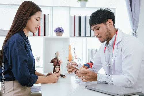 Asian doctor consults with patient in brightly lit clinic. Doctor discusses patient's diagnosis and treatment plan, provides expert advice and medical care in a professional environment.