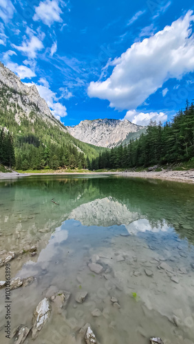 Serene alpine lake Gruener See reflects majestic mountain peak Messnerin, Hochschwab region, Styria, Austria. Wanderlust Austrian Alps. Clear water mirrors the towering ridges and lush idyllic forest photo