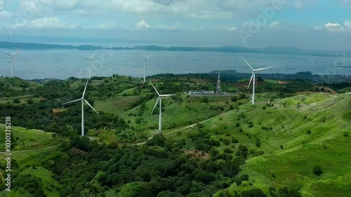 Aerial view of street on green hills with installed wind mills. Sea with islands during cloudy day in Philippines, Rizal Pililla. Wide shot. photo