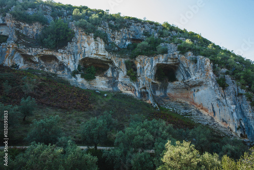 a dramatic limestone cliff with natural caves embedded within it, likely part of the Buracas do Casmilo area in Portugal photo