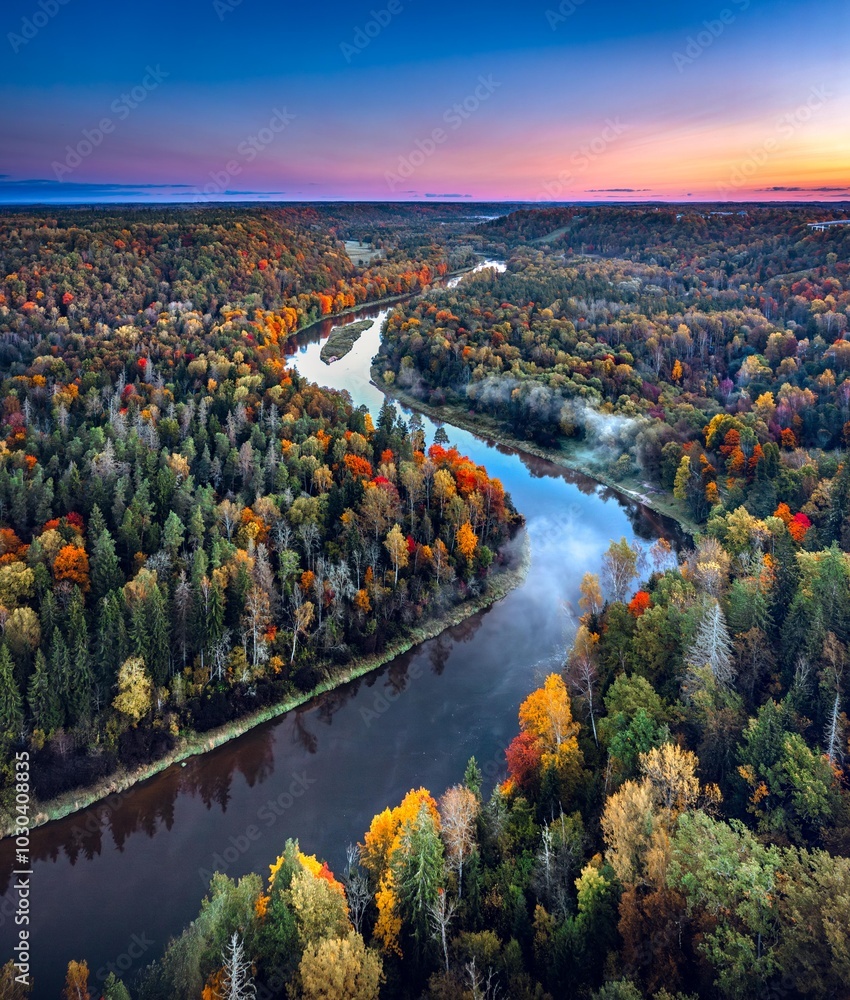 Colorful sunrise over the Gauja National park valley. Sigulda city panorama from drone with forest in autumn colors.