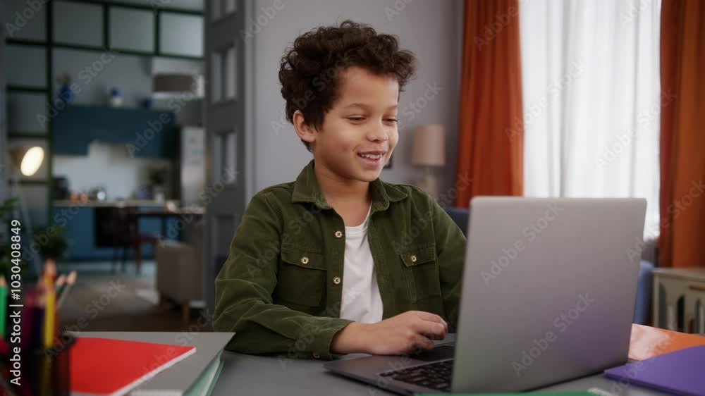 Smiling little African American boy son kid child pupil at home table talking online video call conference chat distant study education e-learning internet laptop computer talk with teacher tutor Smiling little African American boy son kid child pupil at home table talking online video call conference chat distant study education e-learning internet laptop computer talk with teacher tutor